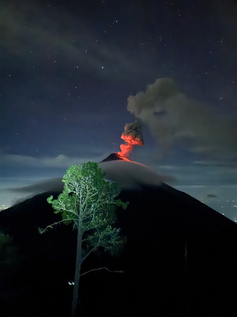 A volcano erupting with glowing lava at night beneath a starry sky